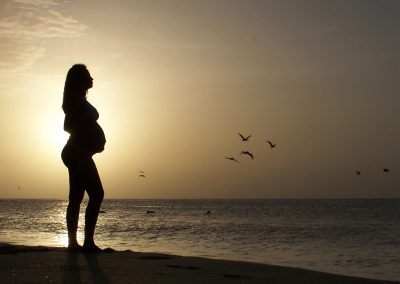Femme enceinte sur la plage au coucher de soleil